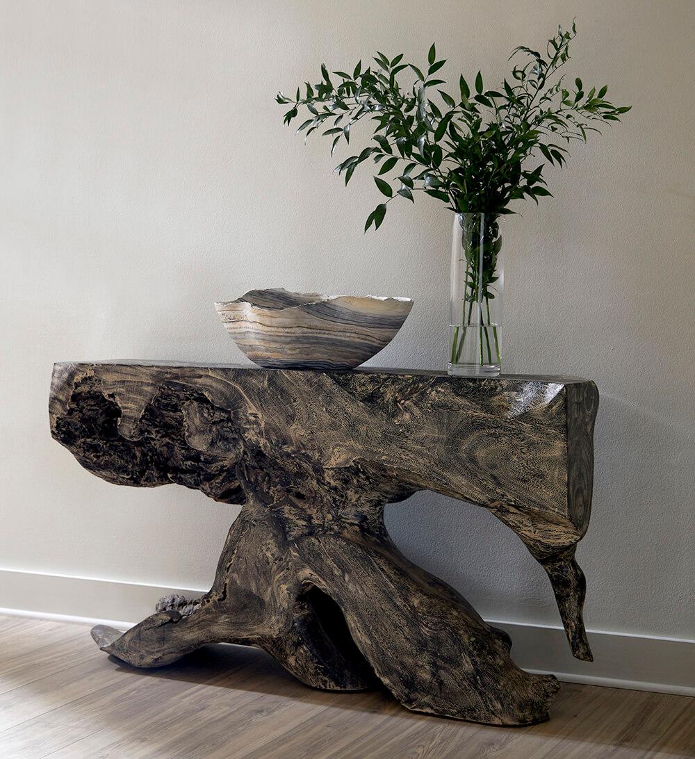 The cut of a fallen tree transformed into a stunning console table with a gray stone finish. 